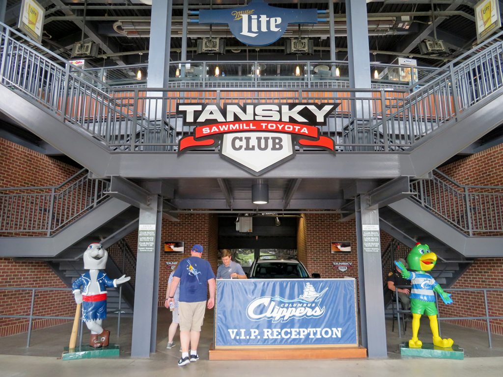Two ceramic bobblehead mascots welcome people to a VIP entrance with a sign above that says "Tansky Sawmill Toyota Club."