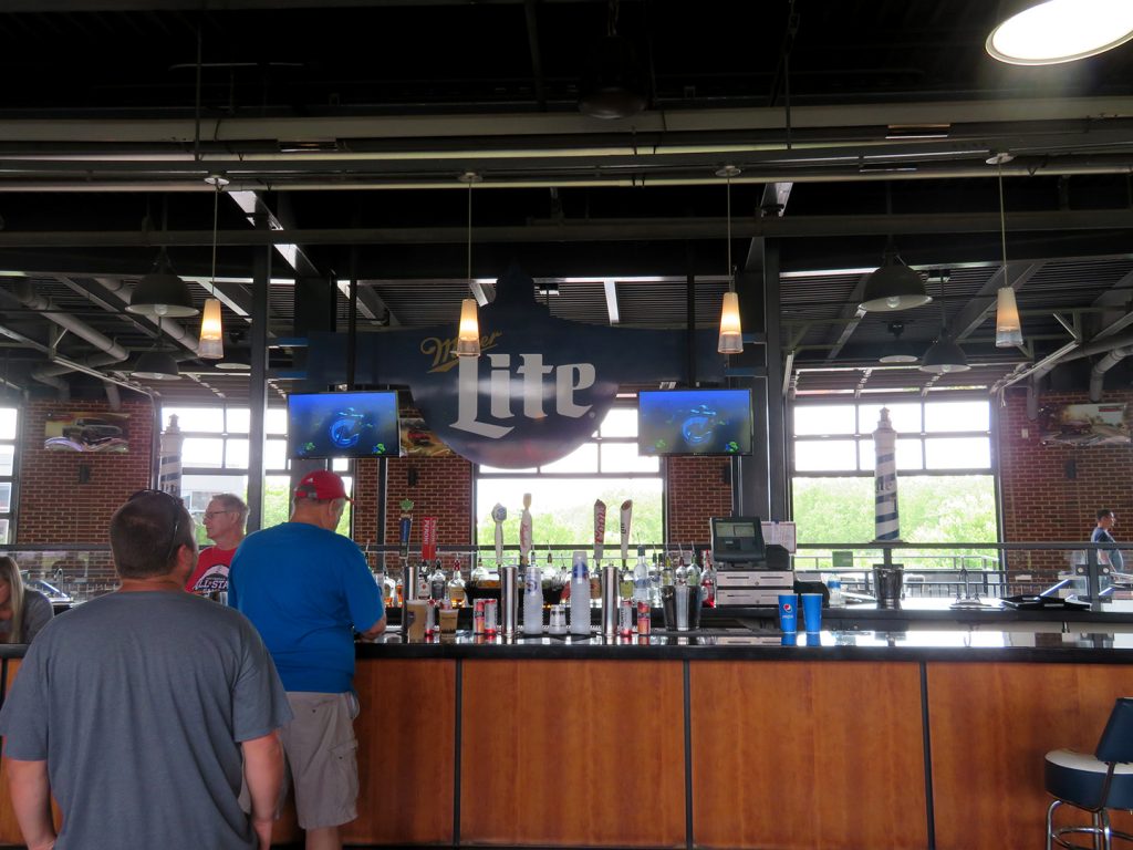 People stand in line to order a drink at a large bar at a baseball stadium.