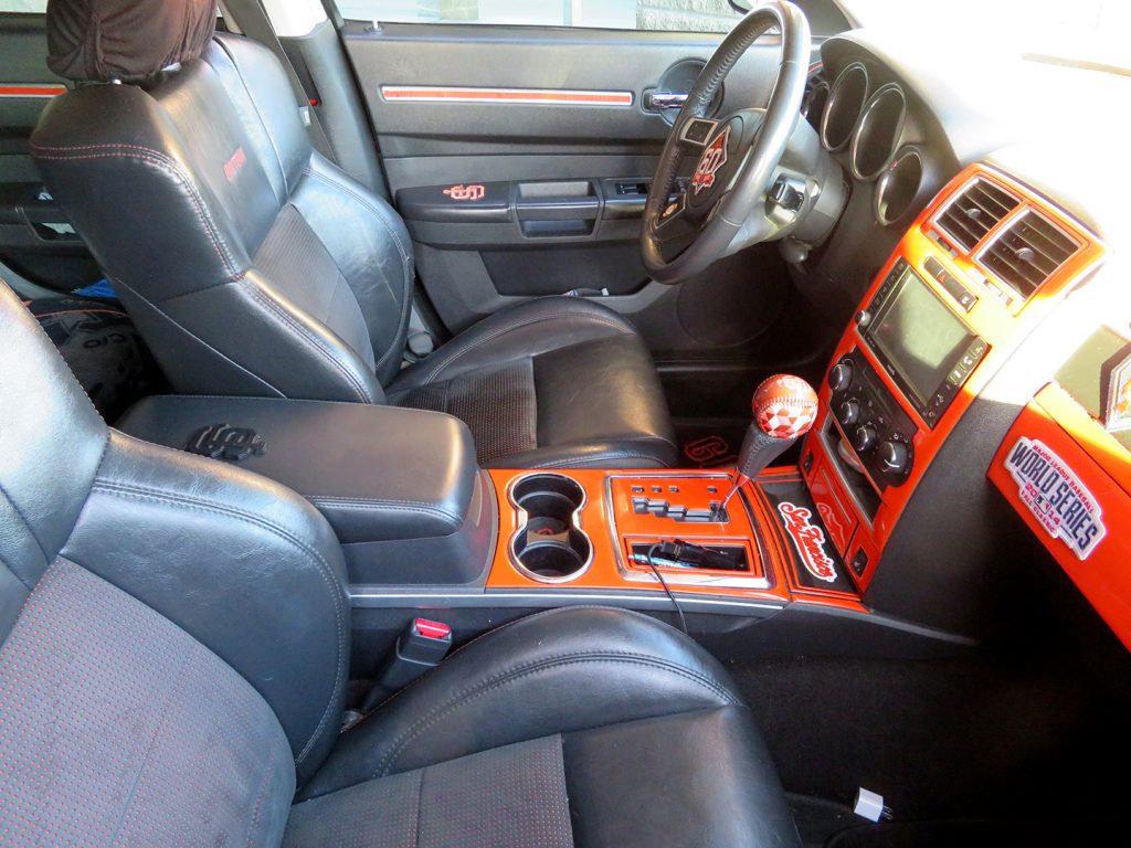 A view of the interior a San Francisco Giants orange colored 2008 Dodge Charger that is covered with Giants logos.