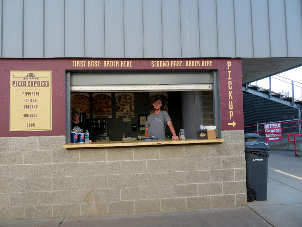 A cinder block concession stand with a sign that says "Southpaw's Pizza Express."
