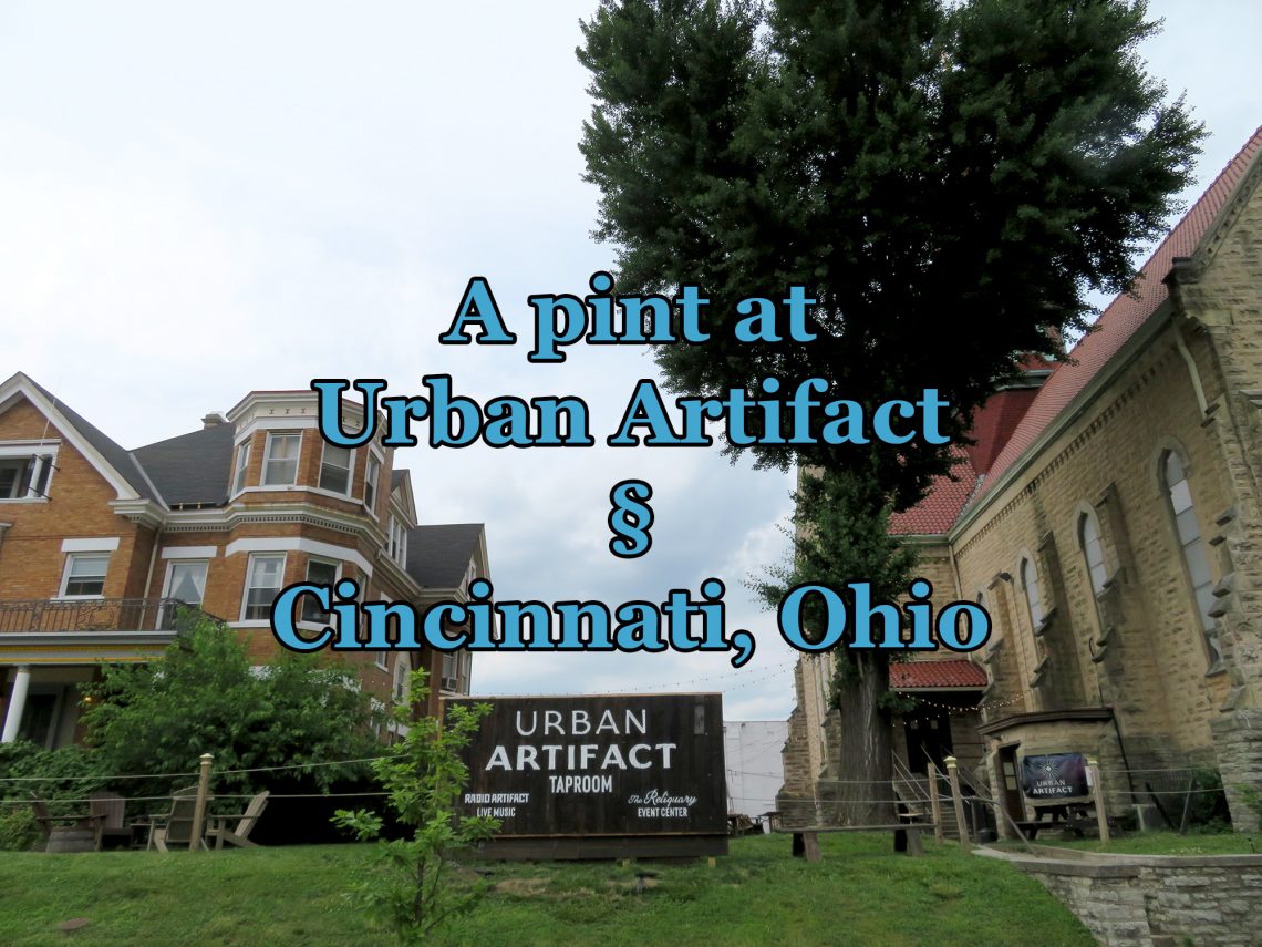 Overview of a large, brick house and a brick church with a patio in between them. Text overlays the image saying "A pint at Urban Artifact in Cincinnati, Ohio.