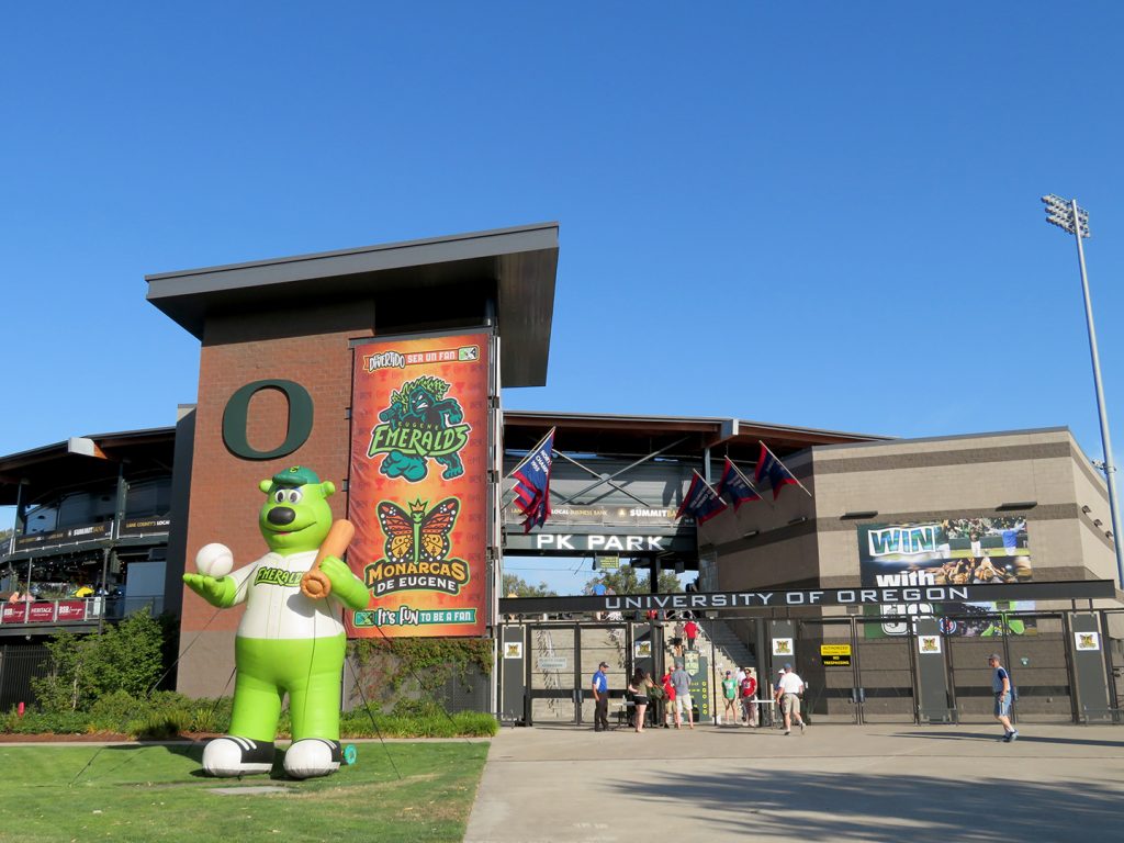 Home plate gates to PK Park with inflatable Sluggo mascot outside and a banner behind it with the Eugene Emeralds and Monarcas de Eugene logos.