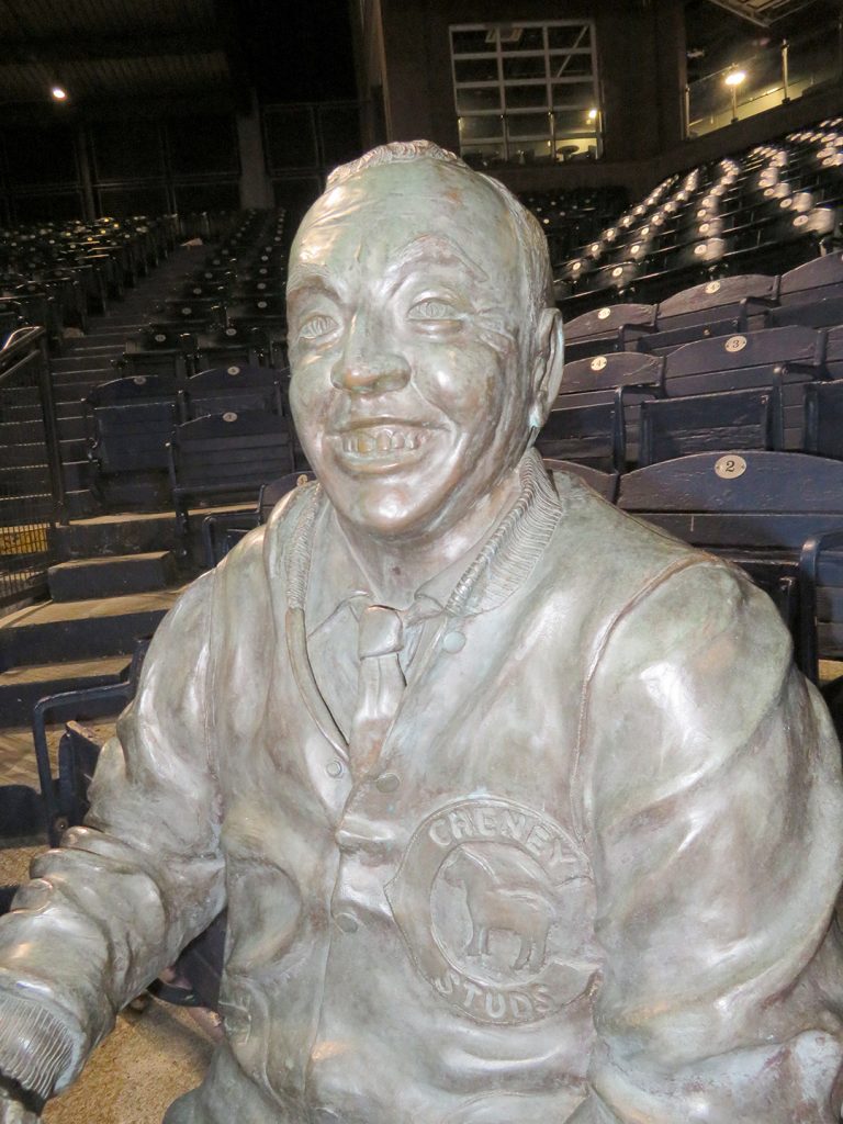 Closeup of a bronze statue of Ben Cheney smiling while sitting in a seat at a Tacoma Rainiers baseball game.