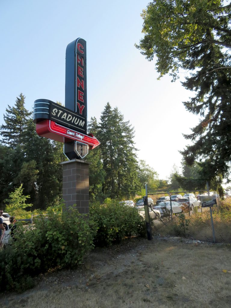 Large black sign with neon lettering that says "Cheney Stadium" with an arrow pointing to the right.