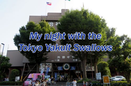 Several trees in front of a large, grey concrete tower with text overlaying the image that says "My night with the Tokyo Yakult Swallows."