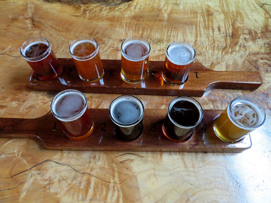 Two flight boards with four tasting glasses of beer on a natural wood table at Ridgewalker Brewing.