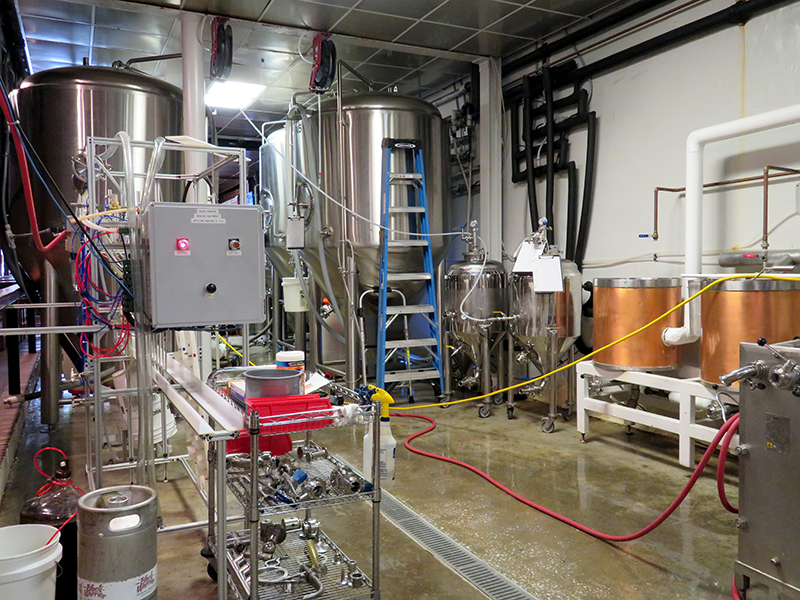 Overview of a small brewery with fermentation tanks to the left.