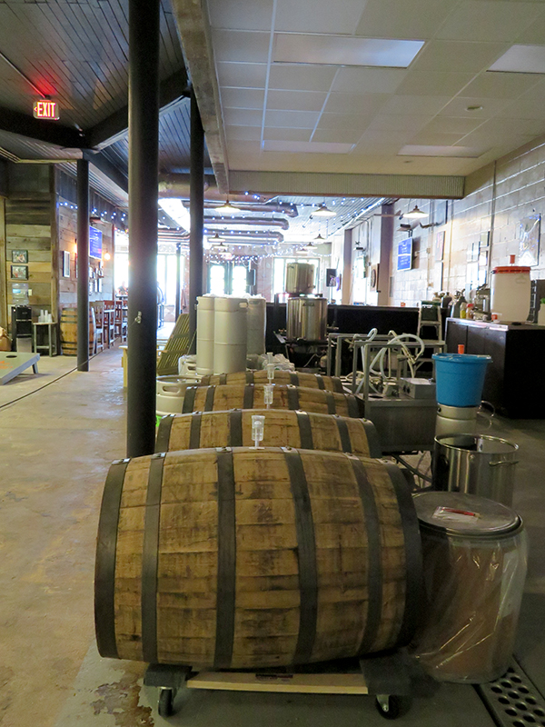 Four wooden barrels in the center with beer kegs in the background.