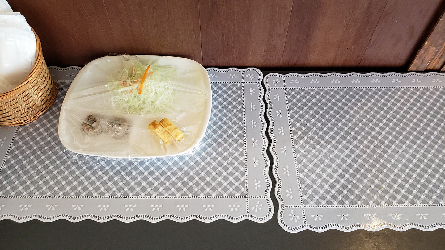 Plastic wrap-covered tray with cabbage and egg omelet on a countertop.