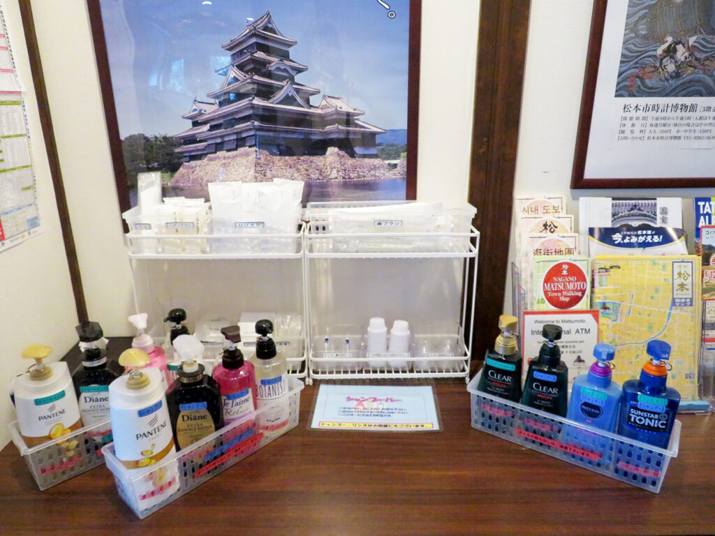 Shampoo bar with multiple products on plastic pump bottles with small containers in background at Hotel Matsumoto Yorozuya.